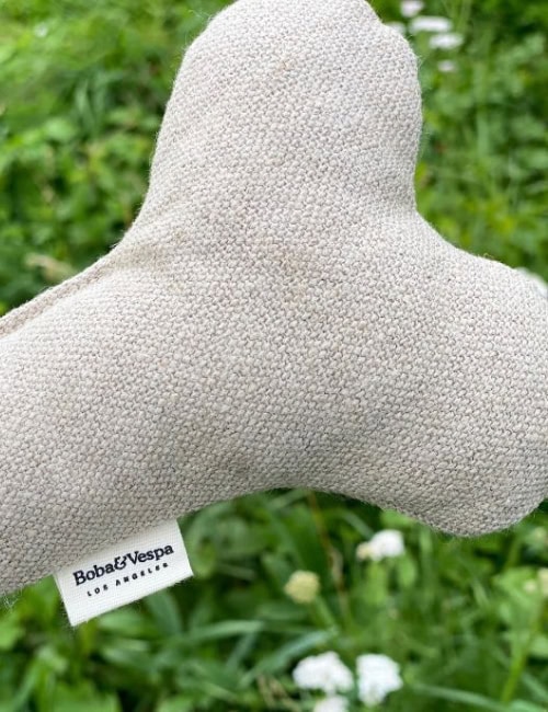 Close-up of a soft linen dog bone toy by The Kind Pet, part of a sustainable pet products range made from natural fibers, as tested by Sustainable Jungle.