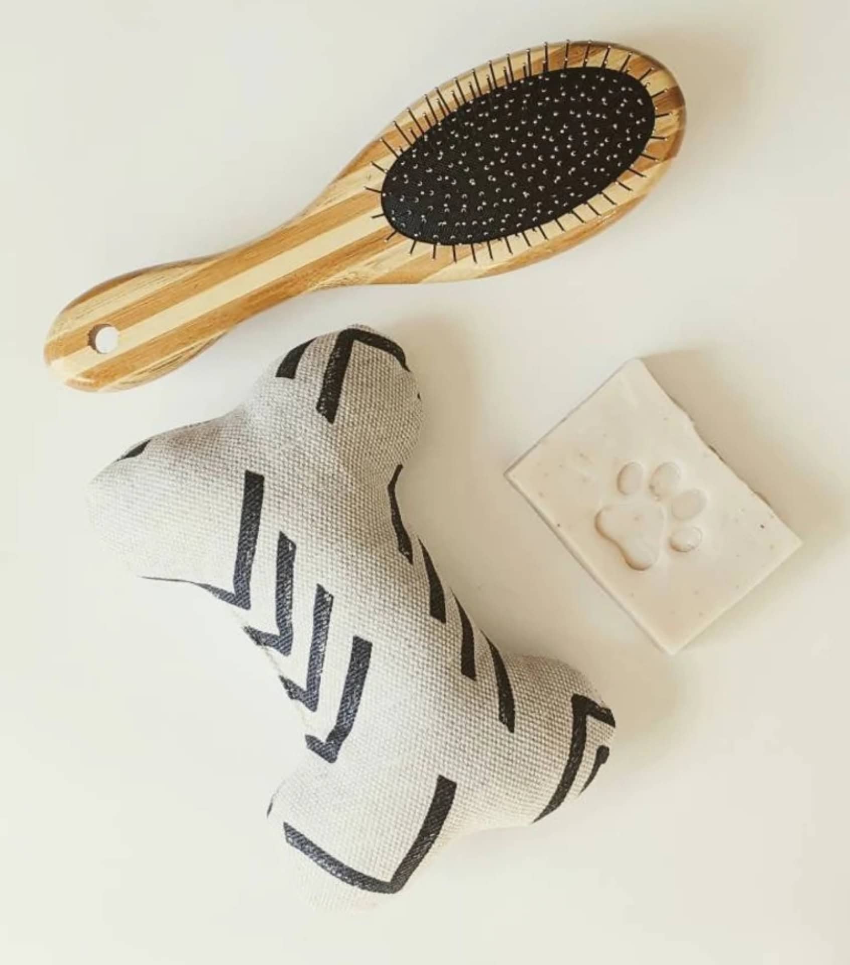 Set of eco-friendly pet grooming accessories including a bamboo brush, natural soap, and linen toy for gentle, sustainable pet care.