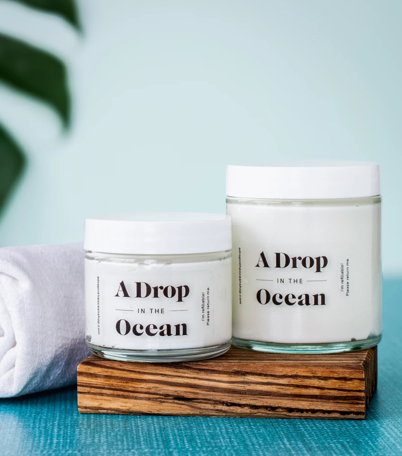 A Drop in the Ocean refillable Daily Facial Moisturizer in two sizes of zero waste glass jars labeled "I'm refillable! Please return me."