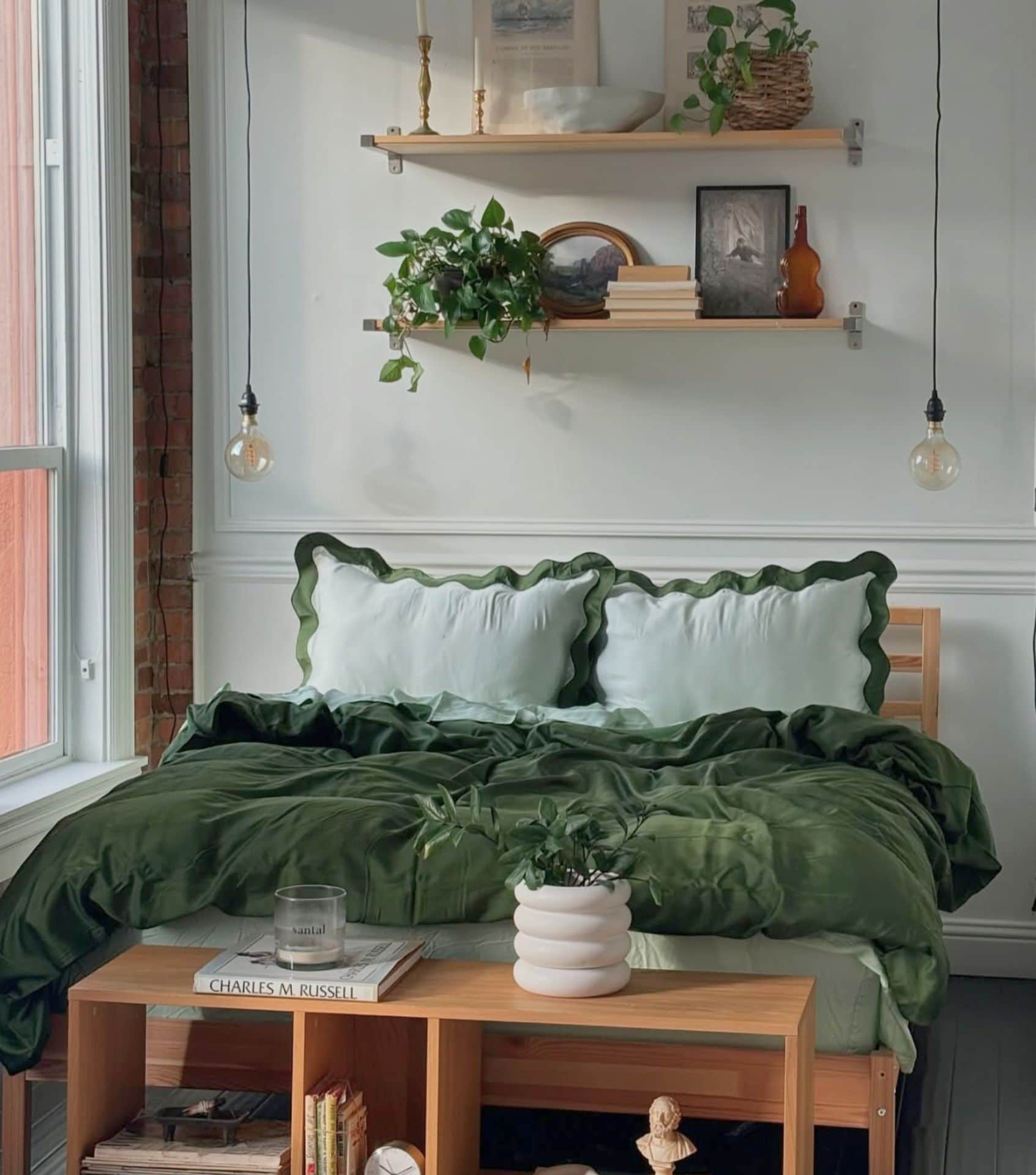 Green and light green scalloped bedding made from sustainable TENCEL™ Lyocell by Eucalypso. This ethical and non-toxic bedding set sits on a wooden bed frame surrounded by natural light and indoor plants for a cozy, eco-conscious look.
