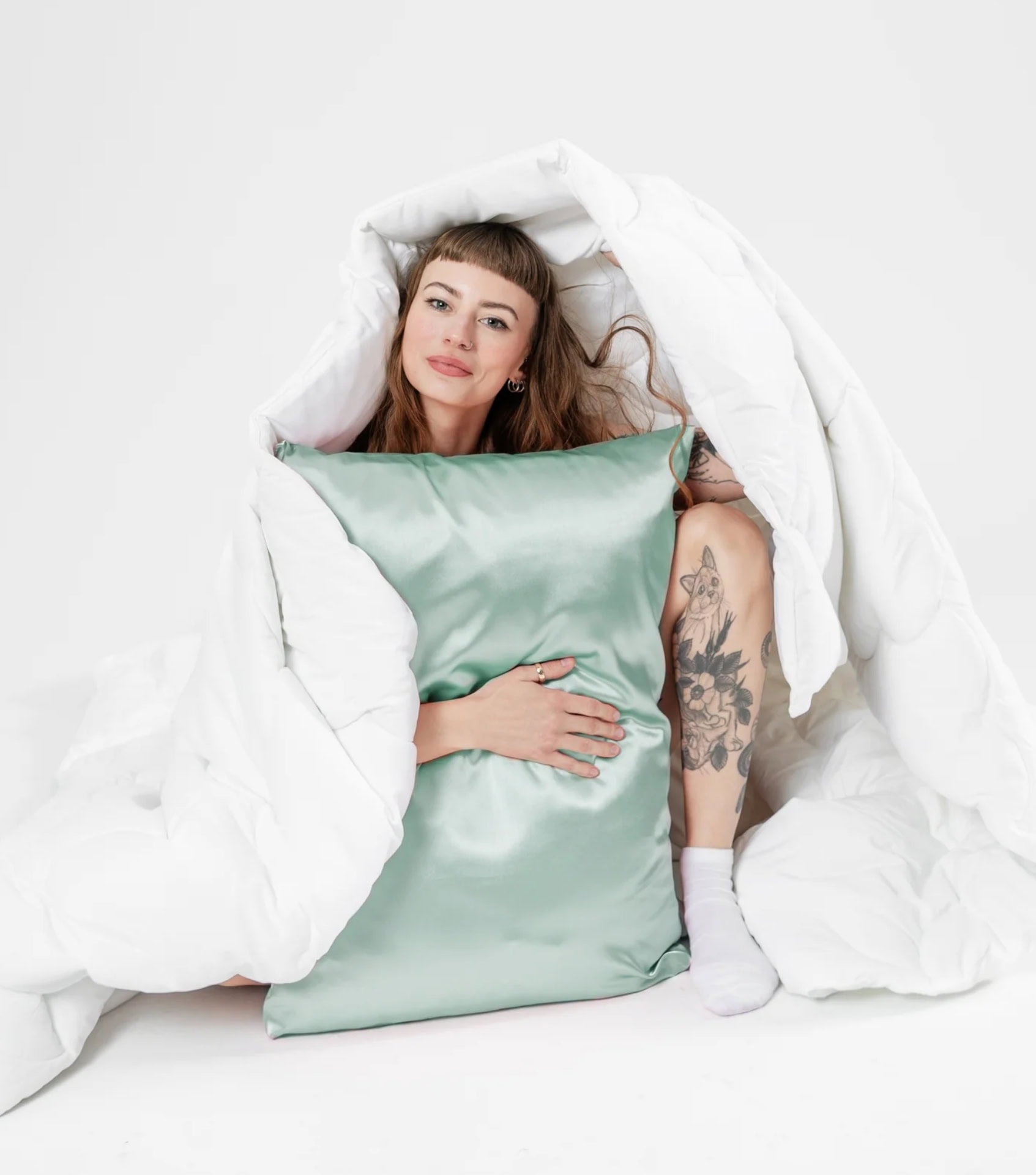 Woman holding sage green vegan silk alternative pillowcase from Maylyn and Co sustainable bedding collection