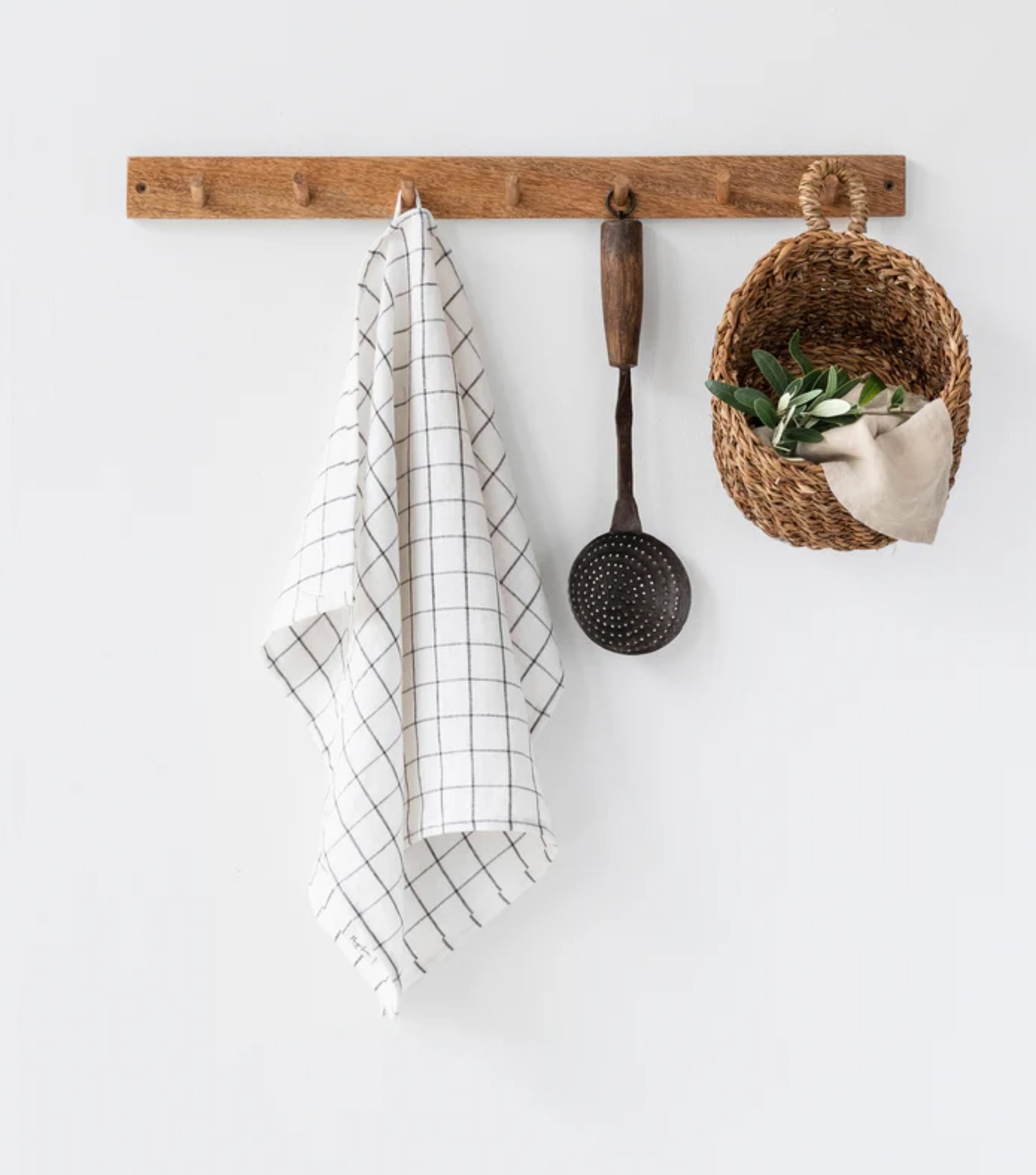 Sustainable home decor with wooden peg rail, kitchen towel, and woven hanging basket