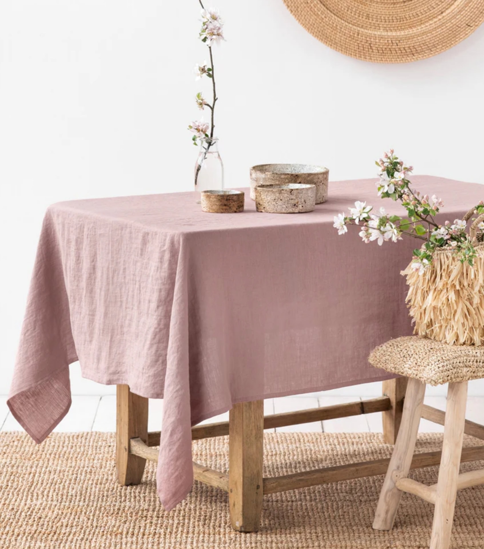 Sustainable home goods featuring dusty pink linen tablecloth with ceramic bowls and natural textures