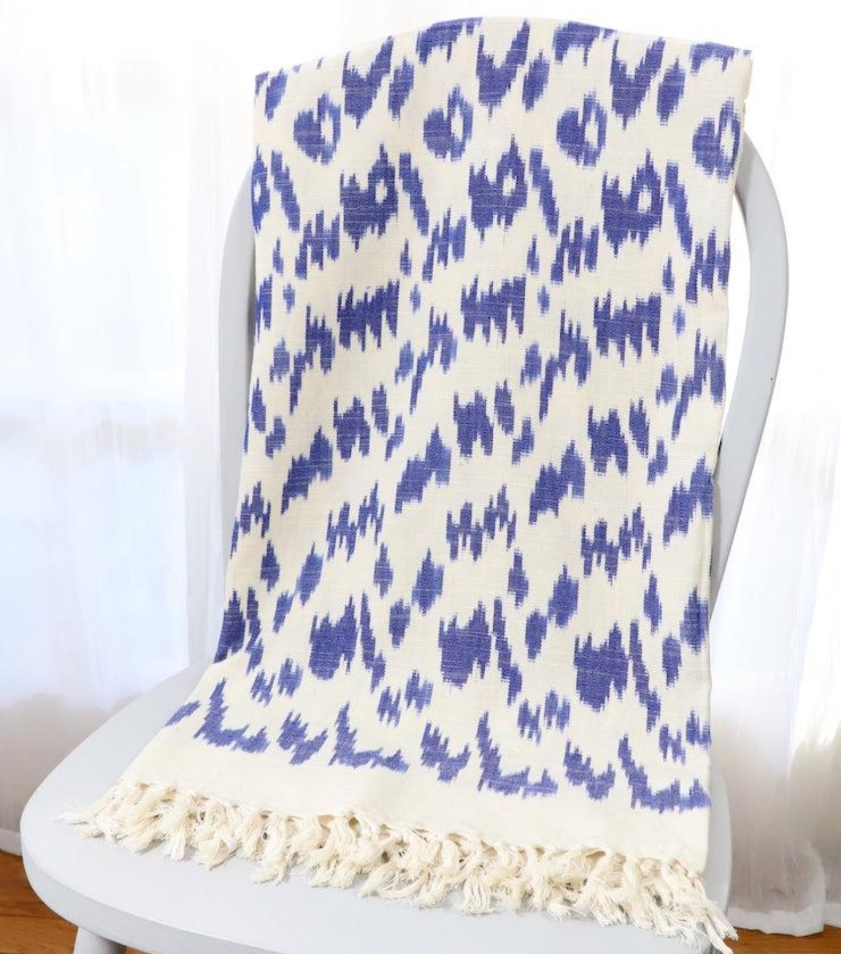 Sustainable home decor featuring blue and white ikat patterned throw blanket with fringe detail