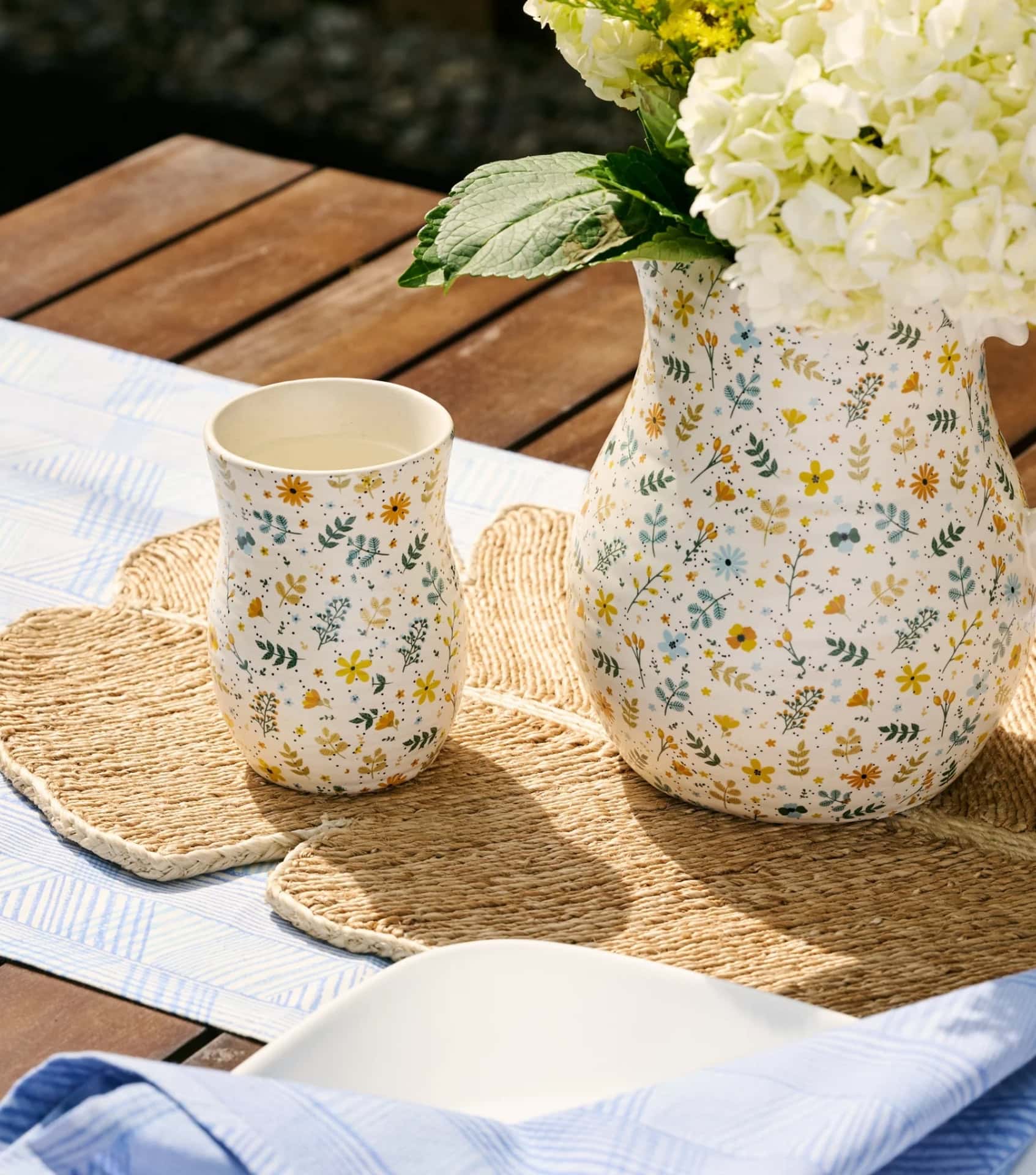Sustainable home goods brands featuring floral ceramic vases and cups on woven placemats