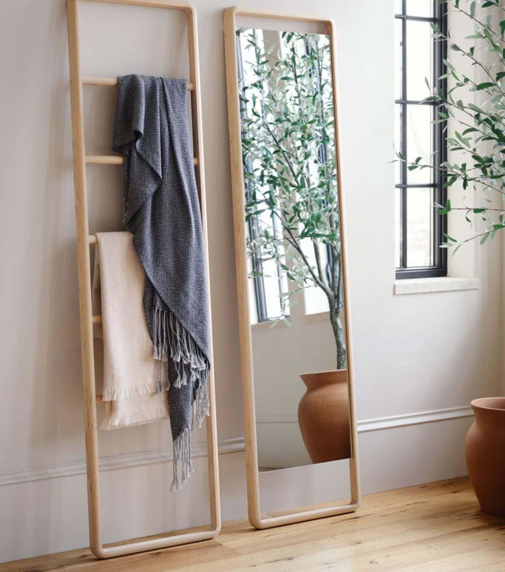 Sustainable home decor with wooden ladder mirror, woven throws, and terracotta planters in minimalist setting