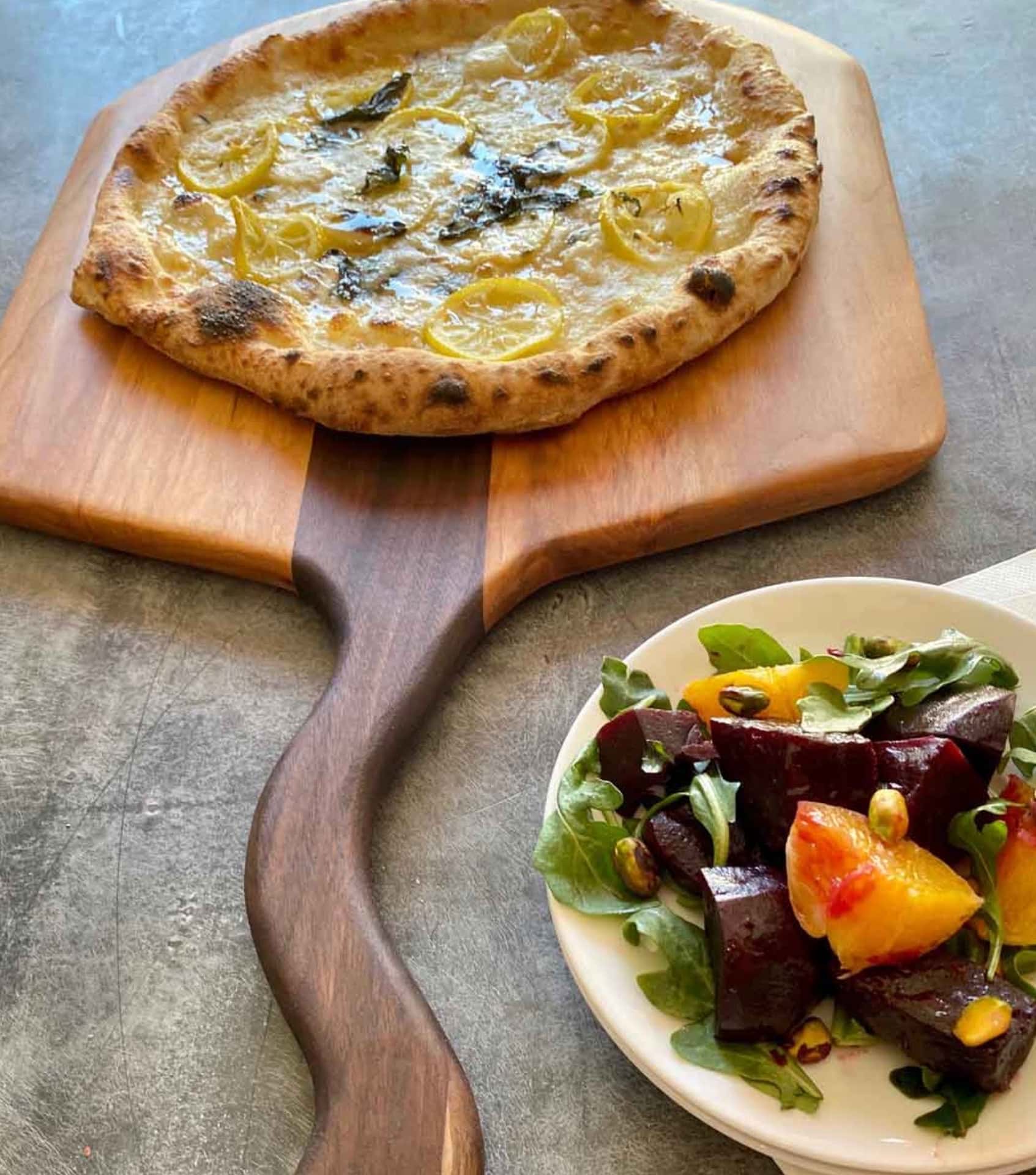 Words With Boards multi-wood cutting board serving homemade pizza showing food-safe finish